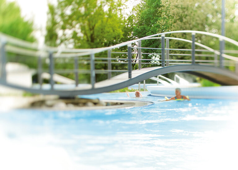 Eine Brücke aus Metall führt über ein Aussenschwimbecken der Terme in Bad Birnbach.