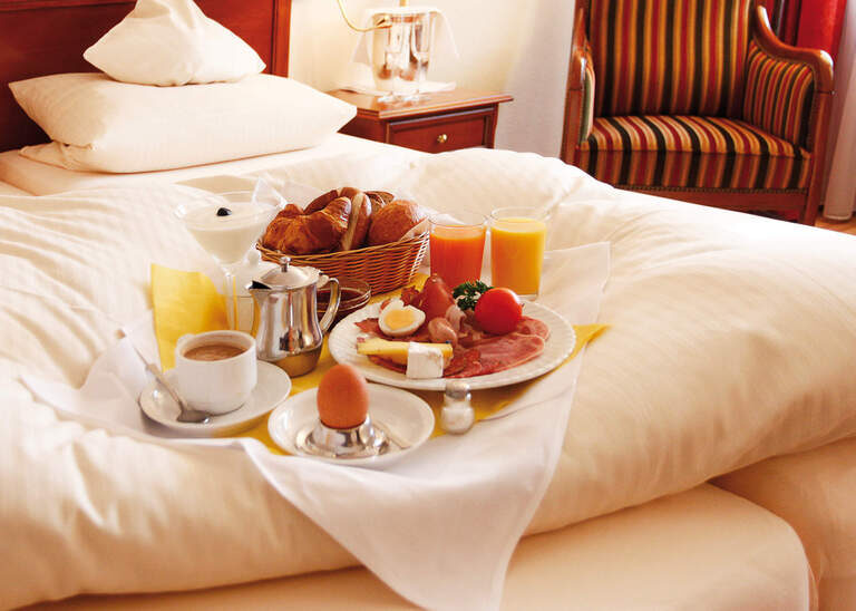 Ein schick angerichtetes Frühstück am Bett mit verschiedenen Säften und Frühstücksei im Hotel Quellenhof in Bad Birnbach.