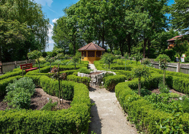 Ein üppiger Garten mit zahlreichen Pflanzen und Bäumen in einem Kurpark von Bad Birnbach.