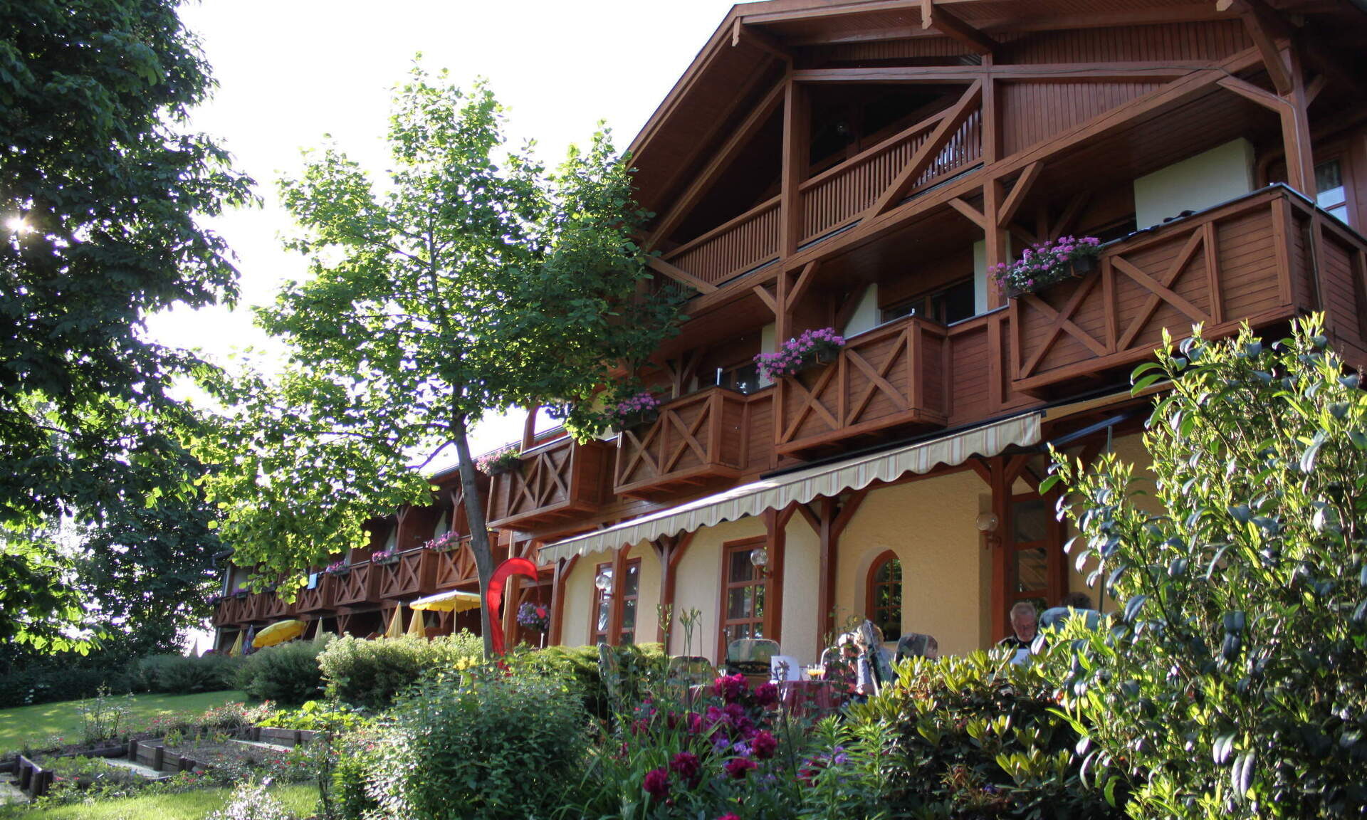 Das Gebäude des Hotels vom grünen und blühenden Garten aus gesehen an einem schönen Sommertag.