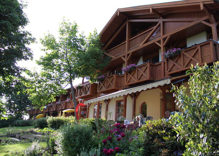 Das Gebäude des Hotels vom grünen und blühenden Garten aus gesehen an einem schönen Sommertag.