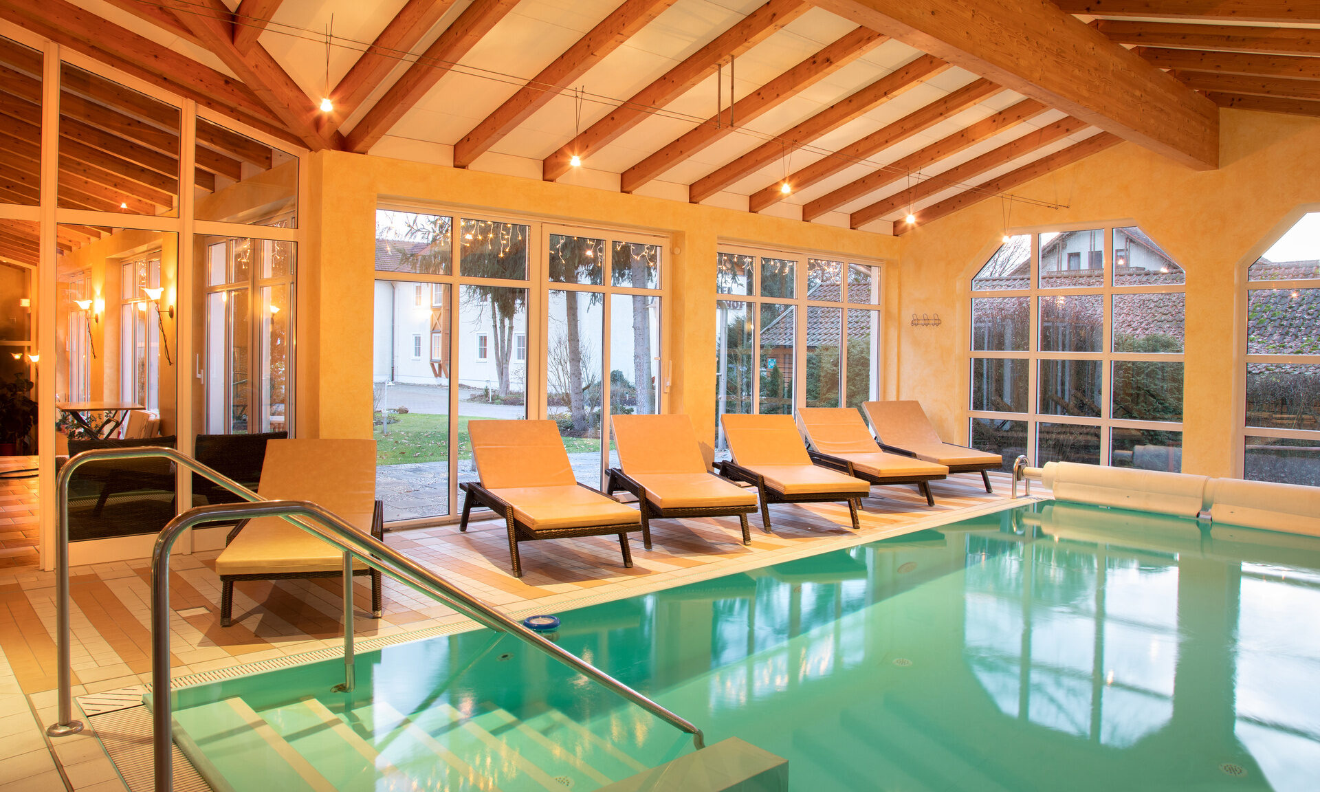 Beheizter Indoor Pool mit Liegen vor einer hellen Fensterfront im Hotel Quellenhof in Bad Birnbach.