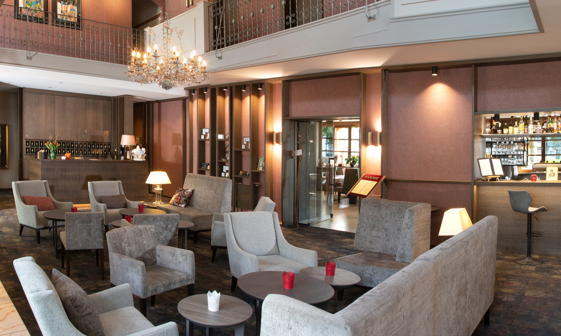 Lichtdurchflutete Lobby des Hotel Quellenhof mit gemütlichen Sesseln und Sitzmöglichkeiten und Bar im Hintergrund.