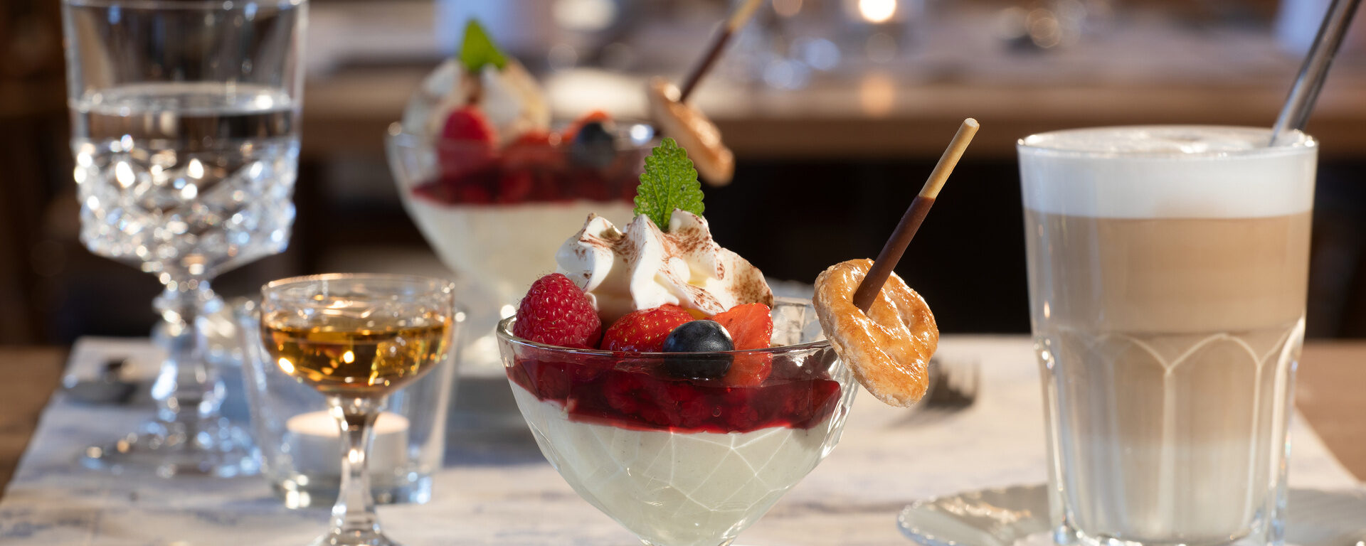 Appetitlich angerichtete Desserts mit einem Glas Latte Macchiato und einem Stamperl Amaretto im Restaurant des Hotel Quellenhof.