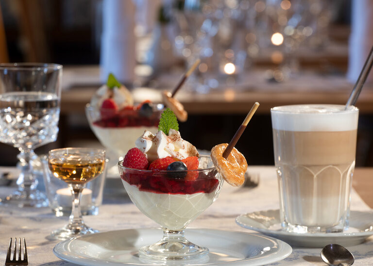 Appetitlich angerichtete Desserts mit einem Glas Latte Macchiato und einem Stamperl Amaretto im Restaurant des Hotel Quellenhof.