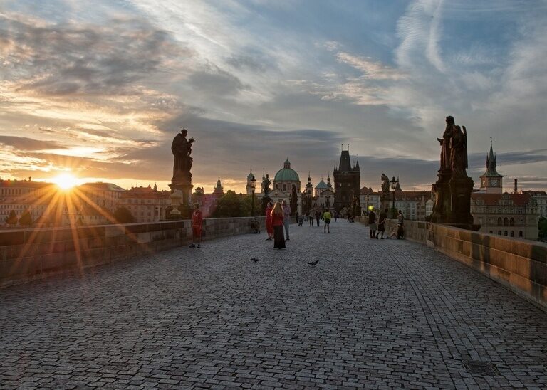 Die Karlsbrücke in Prag mit untergehender Sonne im Hintergrund.