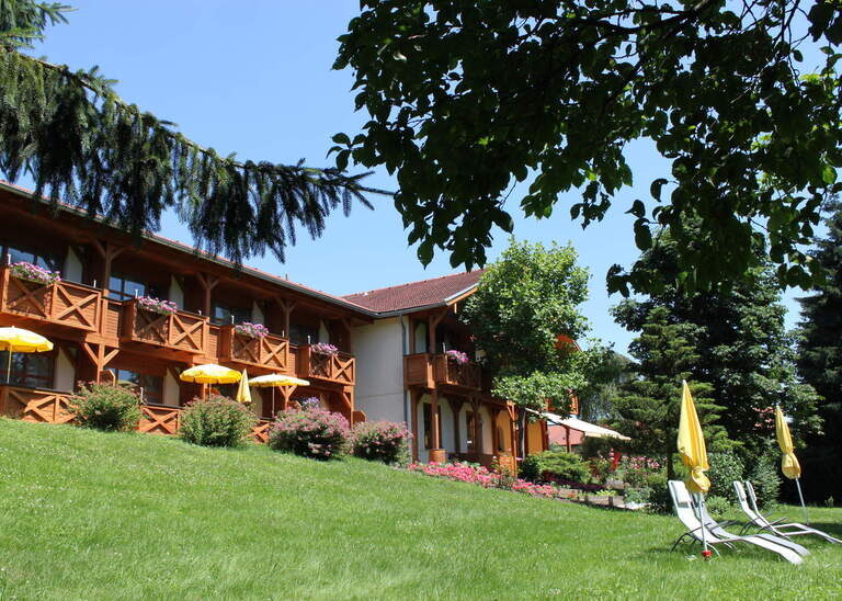 Die Liegewiese im Garten des Hotels Quellenhof in Bad Birnbach an einem schönen Sommertag, mit Liegen und Sonnenschirmen.