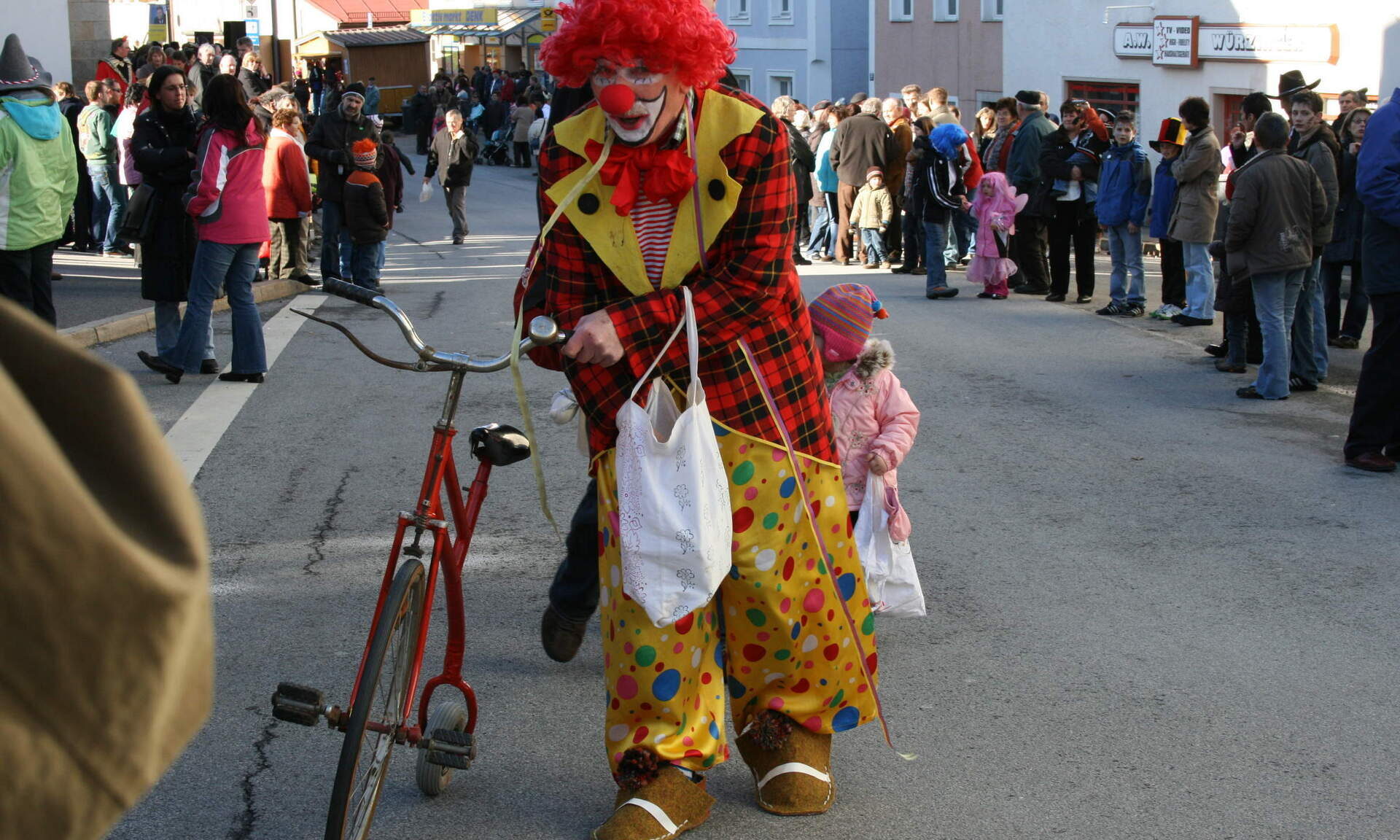 Ein Lustiger Clown ist in der Innenstadt mit einem Fahrrad unterwegs