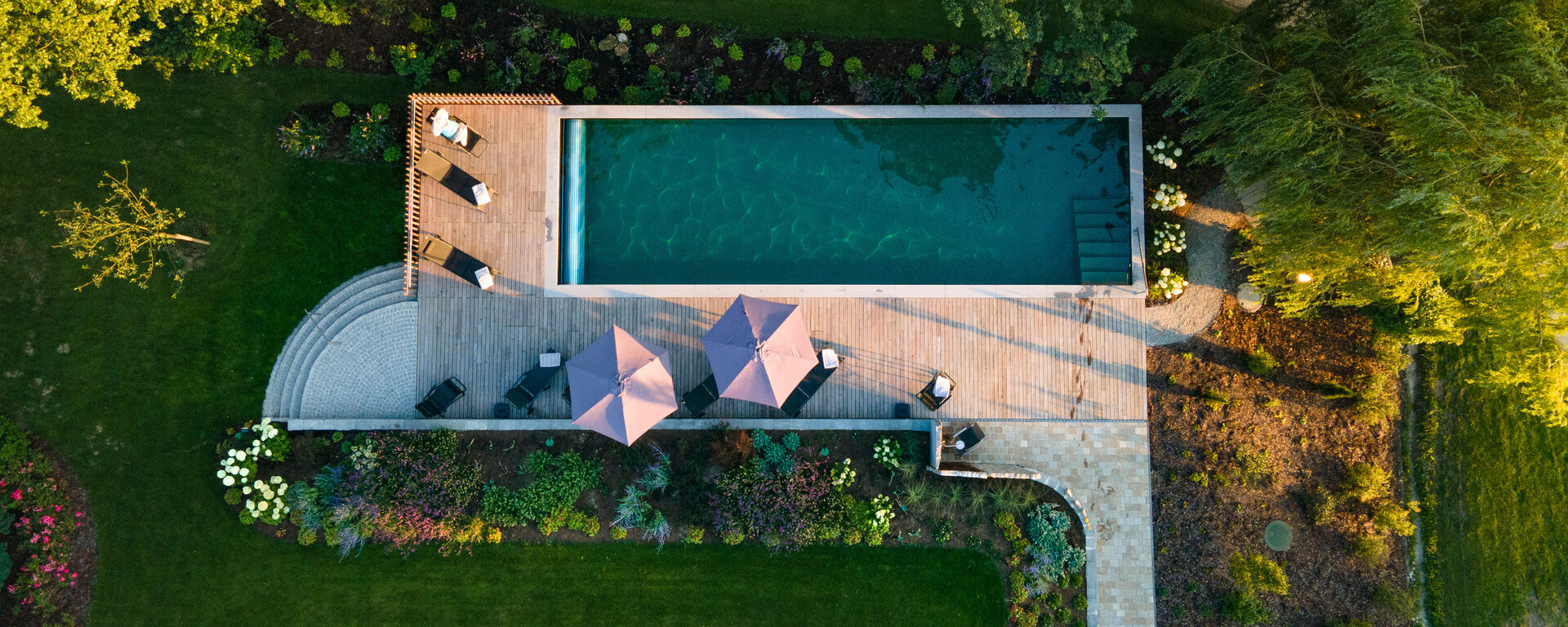 Vogelperspektive des Naturpools und Terrasse mit Sonnenschirmen im Hotel Quellenhof.