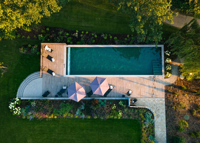 Vogelperspektive des Naturpools und Terrasse mit Sonnenschirmen im Hotel Quellenhof.