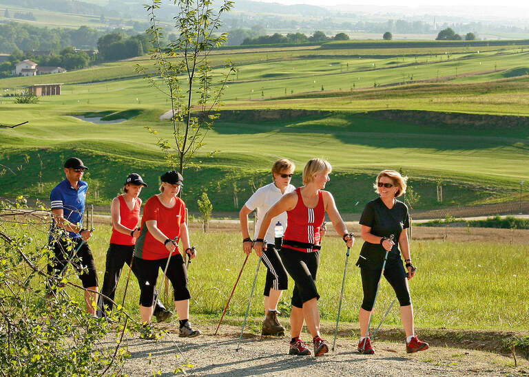 Eine Gruppe von Leuten beim Nordic Walking durch die grüne malerische Landschaft des Rottals nahe Bad Birnbach.