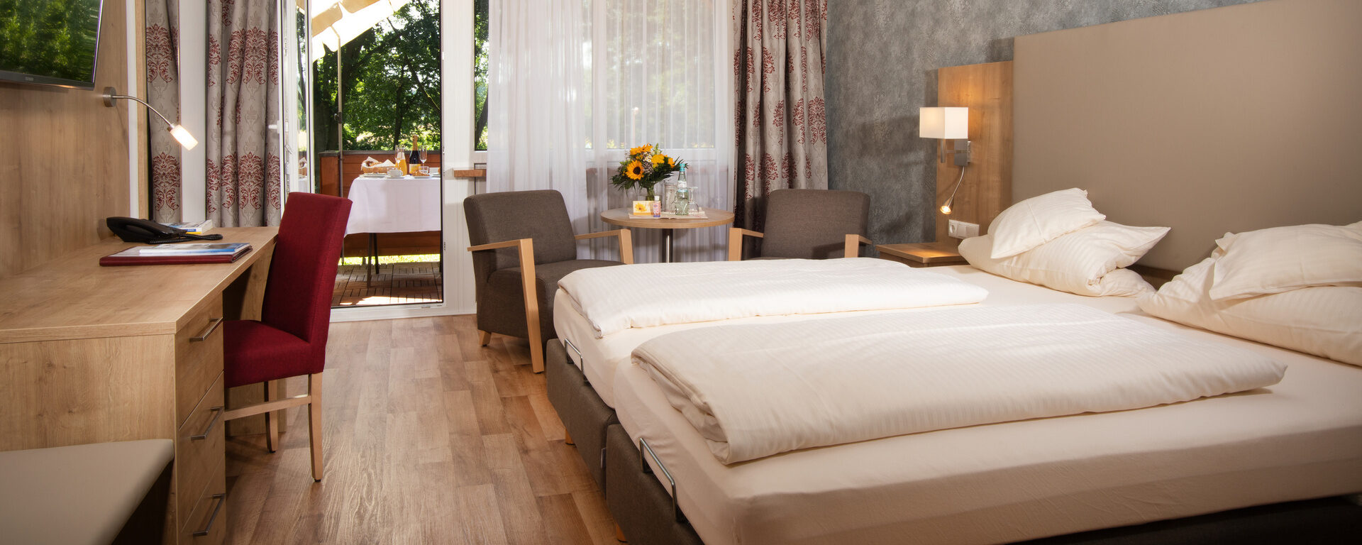 Ein komfortables Doppelzimmer in Südlage des Hotel Quellenhof mit bequemen Doppelbett, Sitzecke und einem Schreibtisch.