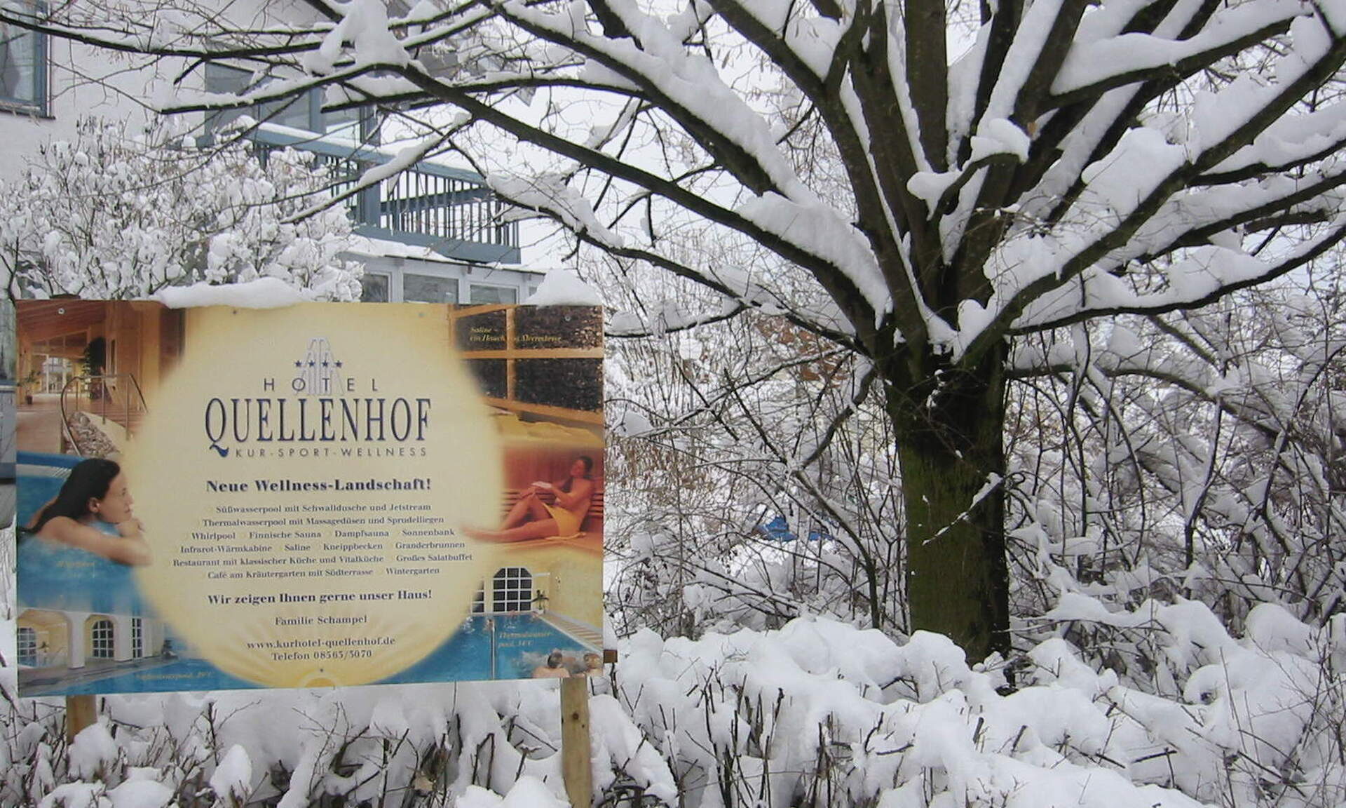 Ein Werbeschild des Hotel Quellenhof Bad Birnbach in einer winterlichen Landschaft mit viel Schnee.