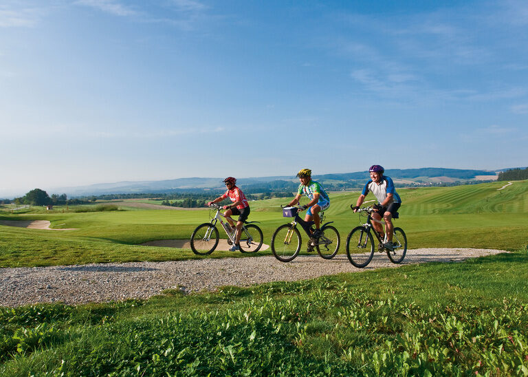 Eine entspannte Fahrradtour rund um Bad Birnbach auf einem Schotterweg mit Blick auf weite Felder und wolkigen Himmel.